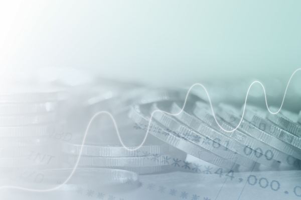 Stacked coins with a wavy line graph over them, representing financial growth or management.