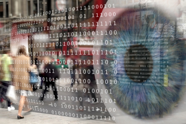 Digital composite of a city scene overlaid with binary code and a close-up of a human eye, representing surveillance and data monitoring.
