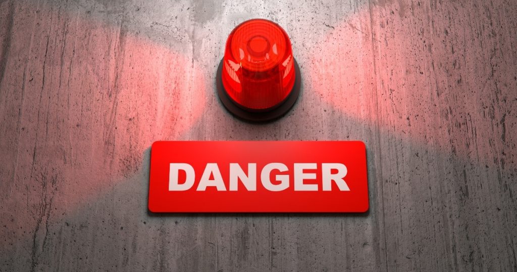 A red alarm light above a "DANGER" sign, symbolizing a false alarm.