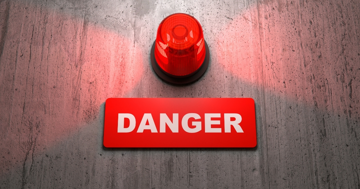 A red alarm light above a "DANGER" sign, symbolizing a false alarm.