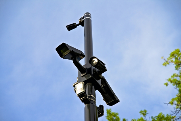 A tall black pole with multiple security cameras and sensors mounted on it against a blue sky, illustrating advanced fixed perimeter security.